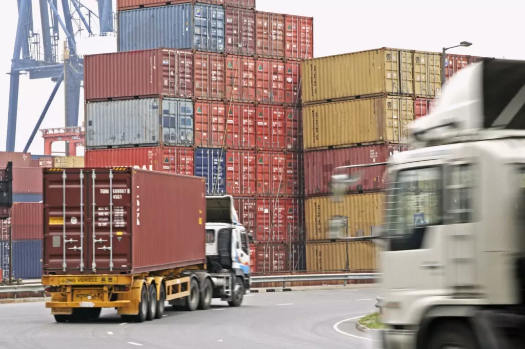 LKWs, die in ein Containerterminal eines Hafens einfahren.