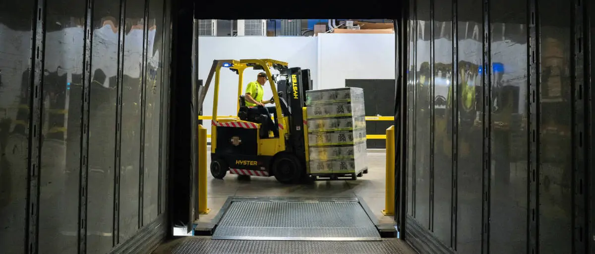 Forklift truck loading paletts of merchandise on a truck trailer. Photo by Elevate on Unsplash